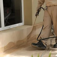 General pest control technician spraying exterior perimeter around a home in Yonkers, NY